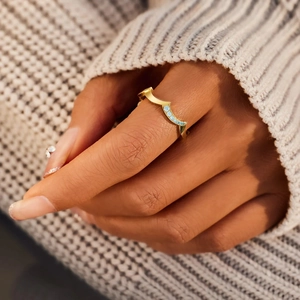 Close-up of wavy S925 silver ring with light blue gemstones on a knit background