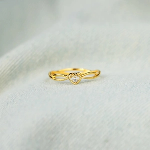 Elegant gold S925 heart ring with crystal center on soft blue textured background
