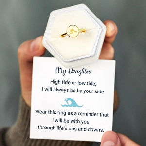 Dettaglio dell'anello dorato con onda in confezione regalo e biglietto d'auguri dedicato
