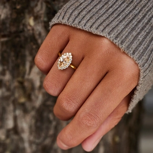 Close-up of a marquise cut champagne gemstone ring with diamond halo on finger
