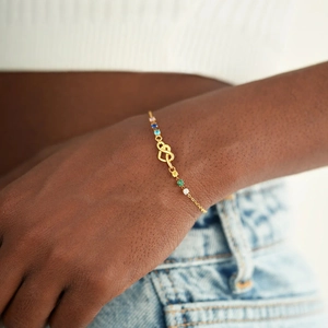 Detail of gold infinity heart bracelet with multicolor stones on a female model wrist