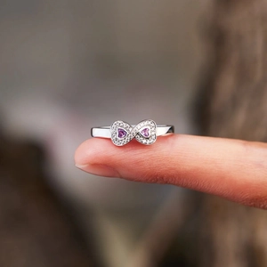 Macro shot of silver infinity ring featuring dual purple heart stones and zircon accents