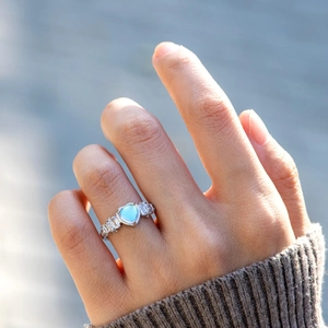 Elegant s925 silver ring featuring a heart-shaped blue zircon and side stones on a finger