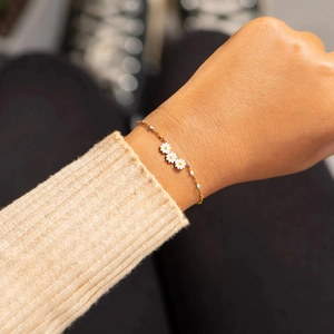 Golden S925 sterling silver daisy bracelet with colorful beads on a knitted sweater cuff