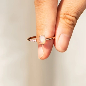 Close-up of a s925 silver rose gold ring featuring an oval opal and pink gemstones