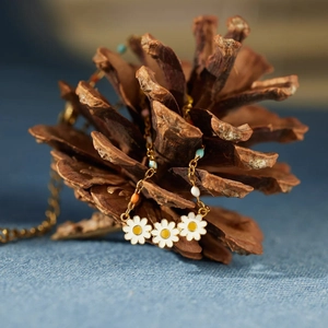 Detail of s925 silver daisy flowers necklace with colorful beads on a pine cone