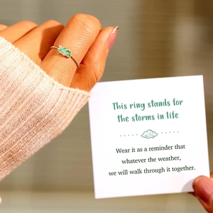 Close-up of a s925 silver green enamel cloud ring worn on hand with a gift card