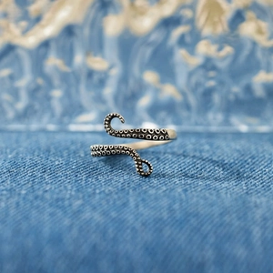 Macro detail of silver octopus tentacle ring with realistic suction cups on denim