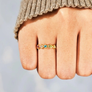 Gold XOXO ring with five multicolor birthstones in a braided band worn by a model