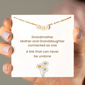 Close-up of gold daisy pendant on floral gift card with blue and orange beads