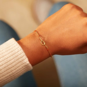 Élégant bracelet nœud doré avec perles rouges au poignet pour un style minimaliste
