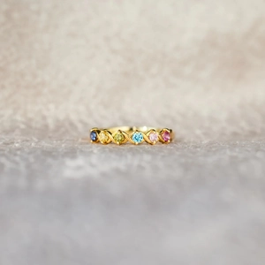 Detail of gold twisted band ring featuring six colorful round-cut gemstones in a row