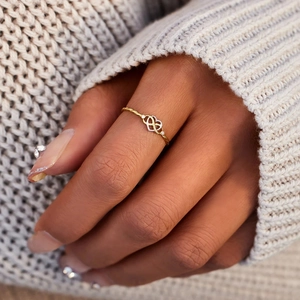 Detail of twisted gold infinity heart ring with pavé stones on finger