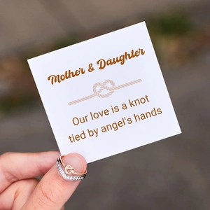 Detail of rose gold heart knot and silver chevron ring set shown with a gift card