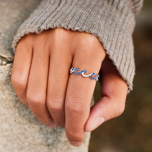 Elegant wave-shaped S925 sterling silver ring with blue cubic zirconia on a model's hand