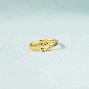 Detail of s925 gold knot ring with multi-color stones on light blue fabric