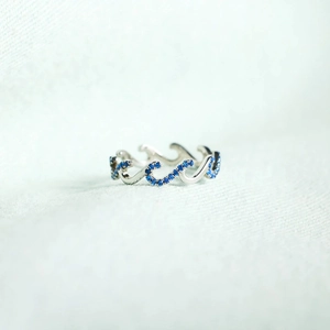 S925 sterling silver wave ring with blue zircons on a textured blue background