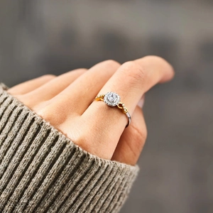 Detailaufnahme eines zweifarbigen Silberrings mit Zirkonia-Halo auf einem Finger getragen