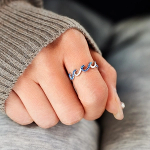 Macro shot of s925 silver wave ring set with blue zircon crystals on a female finger