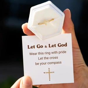 Détail d'une bague croix dorée sertie de zircons avec son coffret en velours blanc