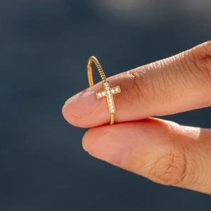Gros plan détaillé d'une bague croix dorée avec anneau torsadé et pierres en zircone