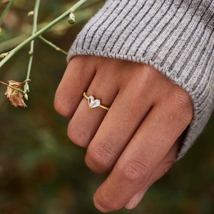 Macro shot of gold pear-cut stone heart ring with elegant twisted rope band on hand
