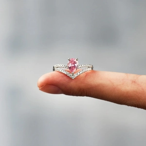 Detail of a pear-shaped pink gemstone ring with a V-shaped pave diamond silver band