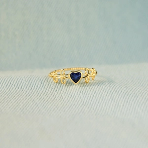 Bague élégante en or torsadé avec saphir bleu en forme de cœur sur tissu bleu texturé