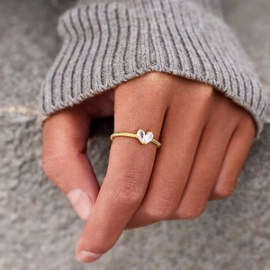 Detail of twisted gold ring band featuring symmetric pear-cut white gemstones in heart shape