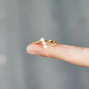 Detail of s925 silver ring featuring three pearls and pave-set zircons in gold finish
