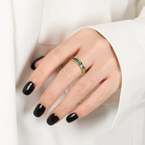 Close-up of a gold ring with emerald green zircon gemstones worn on a hand