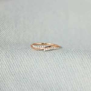 Elegant rose gold wave ring with double row of pavé diamonds on blue denim background