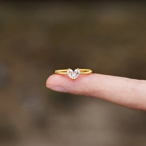 Macro detail of gold pear-cut gemstone heart ring with twisted band design
