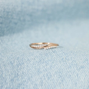Elegant rose gold wave ring with sparkling pave stones on blue denim background