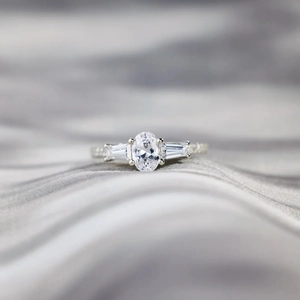 Three-stone S925 sterling silver ring with oval-cut center stone on grey silk fabric