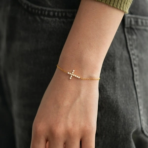 Elegant gold S925 sterling silver cross bracelet featuring sparkling pavé gemstones on wrist