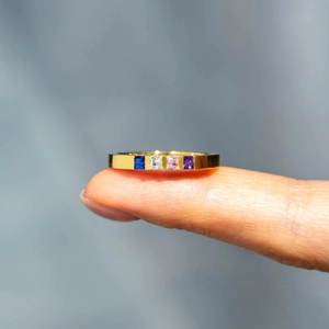 Macro shot of 925 silver gold ring with four colorful square-cut stones on a finger