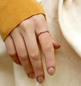 Detail of s925 silver infinity ring with sparkling zircon stones on female finger
