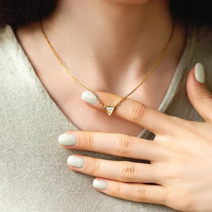 Close-up of s925 silver opal triangle pendant necklace on model wearing grey sweater
