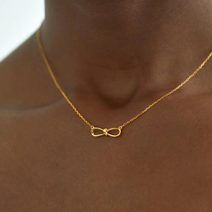 Minimalist S925 sterling silver infinity knot necklace in gold finish on collarbone