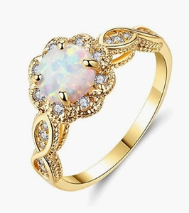 Close-up of golden infinity band ring with white opal center stone and floral halo stones