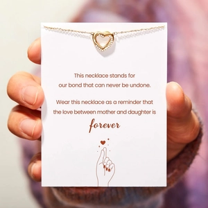 Detailed view of gold double heart pendant with cubic zirconia on gift card for mother