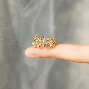 Macro shot of polished gold LOVE letter ring showing smooth texture and elegant script design
