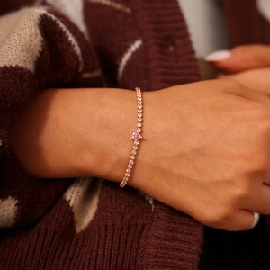 Vue rapprochée d'une pierre rose en cœur et d'un bracelet de tennis sur un poignet
