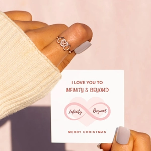 Rose gold infinity heart ring with pavé stones on a gift card message background