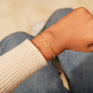 Bracelet couronne s925 en argent doré avec perles colorées sur un pull en tricot