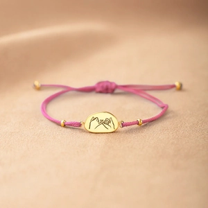 Bracelet ajustable cordon rose avec pendentif doré gravé d'un geste de promesse