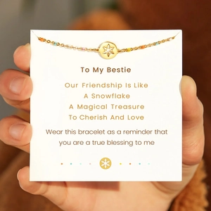 Hand holding S925 sterling silver colorful enamel snowflake bracelet on greeting card