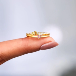 Macro d'une bague dorée double rang avec gemme cœur rose et détails en cristaux