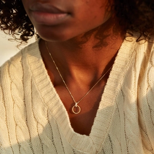 Elegant s925 gold twisted circle necklace on woman wearing a white knit sweater